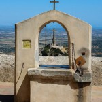 Ein alter Steinbrunnen und Blick auf das Steinkreuz