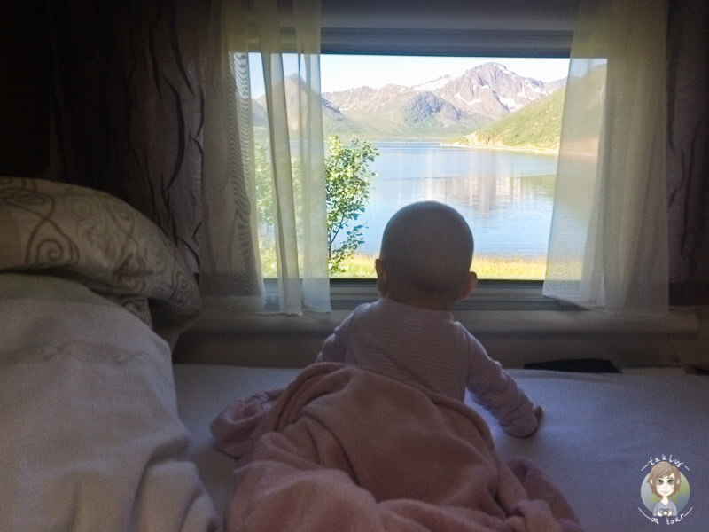 Baby schaut aus Wohnmobilfenster auf Fjord in Norwegen