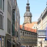 Blick auf ein Gebaeude in Dresden mit schoener Wandbemalung und ein Kirchturm im Hintergrund
