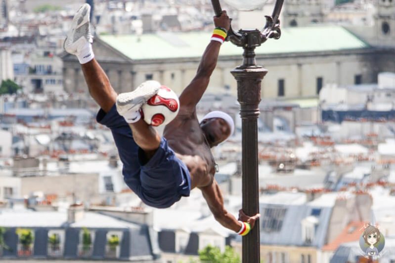 Ein Sportler mit einem Ball an einer STrassenlaterne