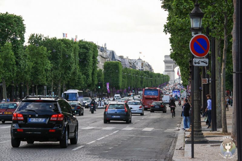 Blick über die Ein Straßenkünstler an der Champs-Élysées mit dem Arc de Triumph im Hintergrund