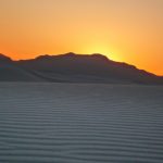 Die Sonne verschwindet hinter einem Huegel in White Sands New Mexico